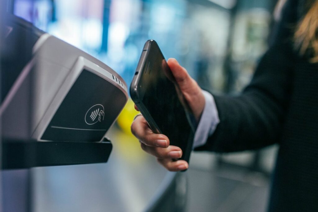 mobile ticketing man holding phone in front of contactless payment accepting station