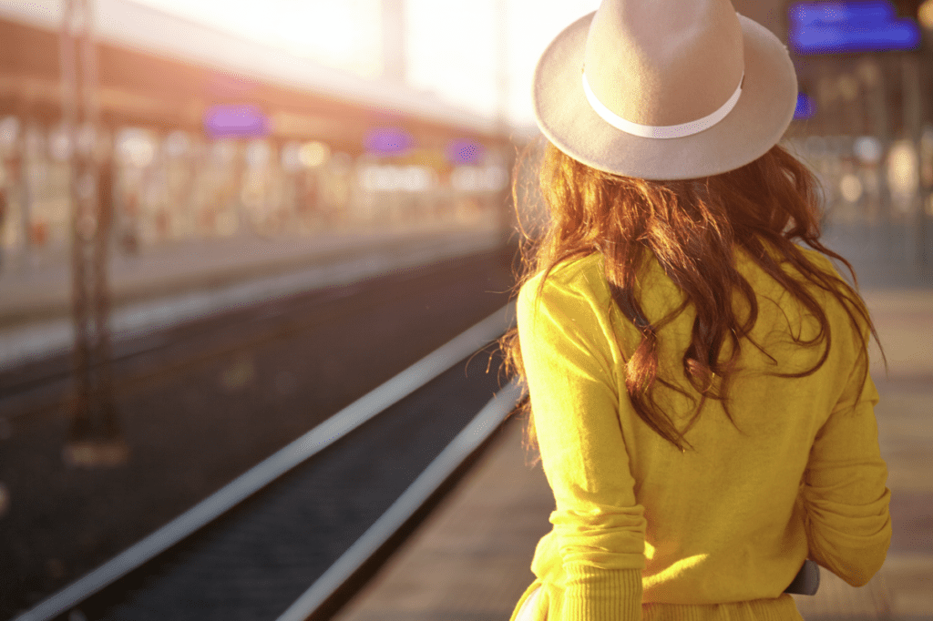 woman in yellow and cream colour hat waiting for train in train station