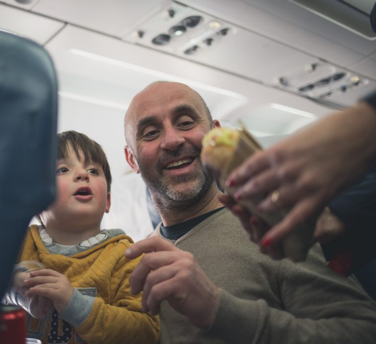 man with child is given food from flight attendant onboard