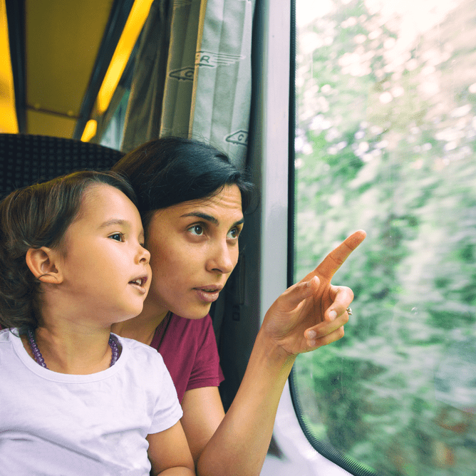 woman showing kid what is outside the window in train