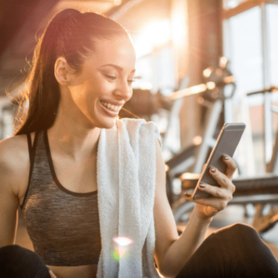 woman smiling at gym looking at phone
